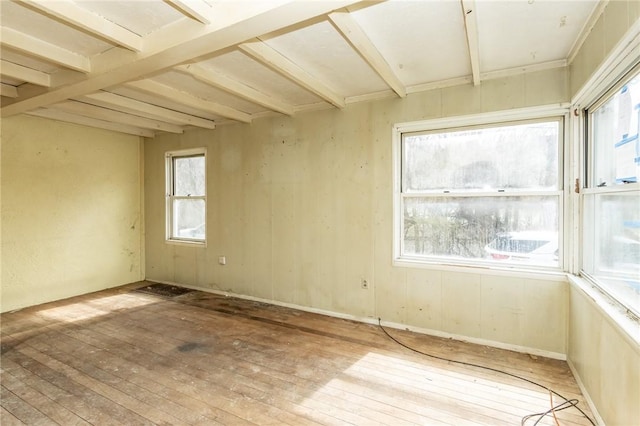 spare room featuring beam ceiling and light wood-style floors