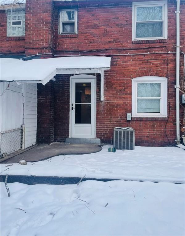 snow covered property entrance featuring central air condition unit