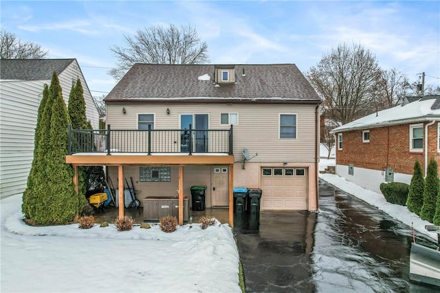 snow covered property featuring a garage, cooling unit, and a balcony