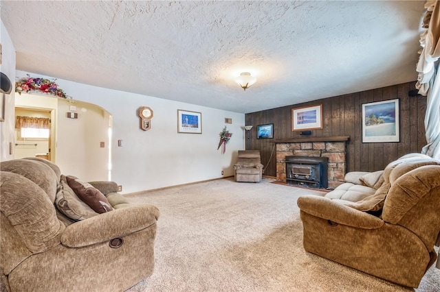 carpeted living room with a textured ceiling and wood walls