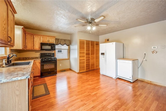 kitchen featuring ceiling fan, sink, black appliances, and light hardwood / wood-style flooring