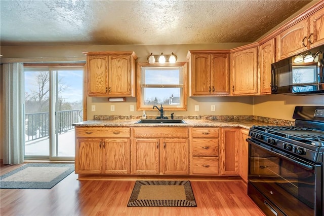 kitchen featuring a textured ceiling, sink, light hardwood / wood-style flooring, and black appliances