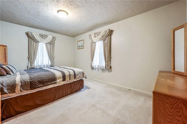 bedroom with light carpet, a textured ceiling, and multiple windows