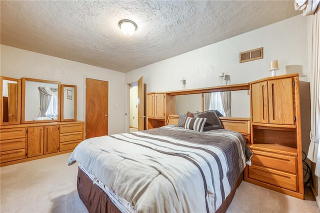 bedroom with light colored carpet and a textured ceiling