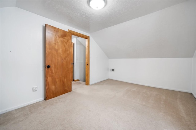 bonus room featuring a textured ceiling, lofted ceiling, and light colored carpet