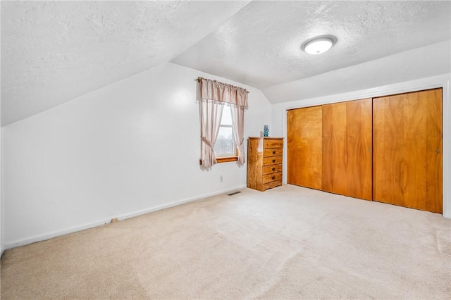 bonus room featuring light colored carpet, a textured ceiling, and vaulted ceiling