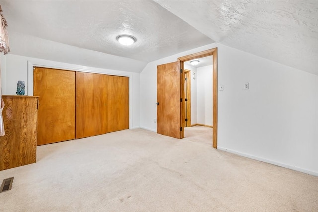 bonus room featuring a textured ceiling, lofted ceiling, and light carpet