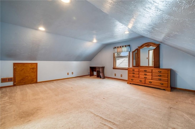 bonus room with a textured ceiling, light carpet, and vaulted ceiling