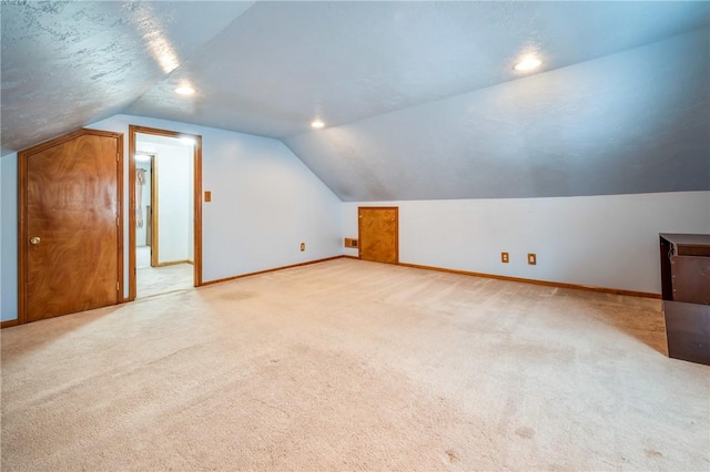 bonus room with lofted ceiling and light carpet