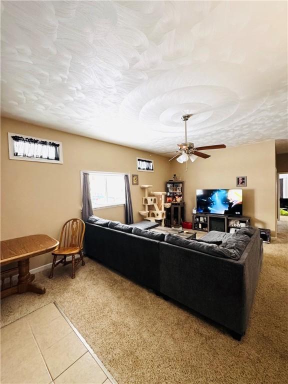 tiled living room featuring ceiling fan and a textured ceiling