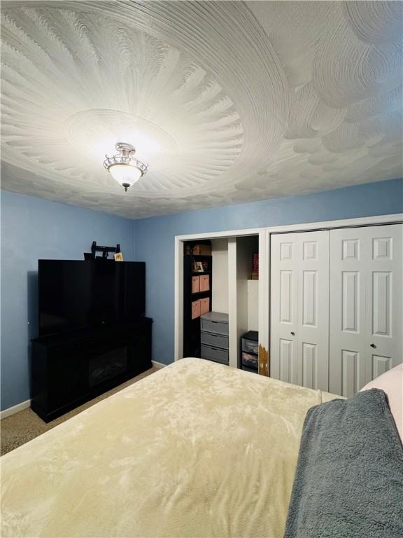 bedroom featuring a textured ceiling, multiple closets, and carpet flooring