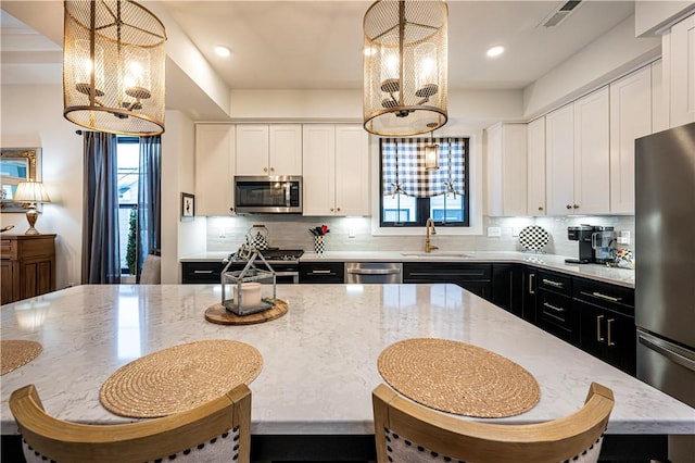 kitchen featuring white cabinetry, hanging light fixtures, sink, and appliances with stainless steel finishes