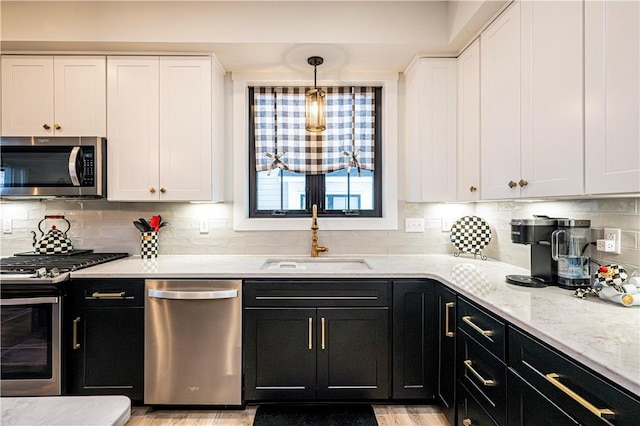 kitchen featuring stainless steel appliances, white cabinetry, hanging light fixtures, and sink