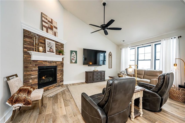 living room featuring ceiling fan, a fireplace, high vaulted ceiling, and light hardwood / wood-style flooring