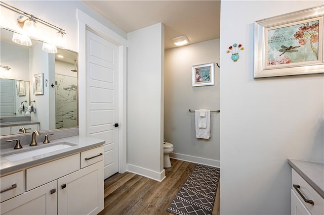 bathroom with vanity, wood-type flooring, toilet, and a shower