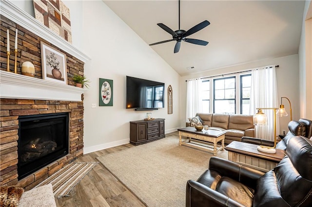 living room with ceiling fan, high vaulted ceiling, a fireplace, and light hardwood / wood-style flooring