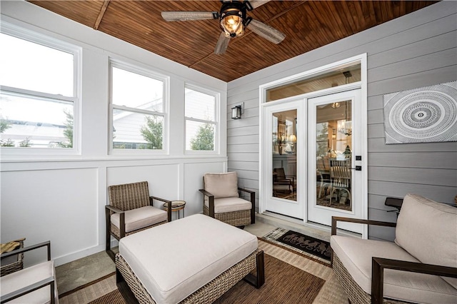 sunroom featuring wood ceiling, a ceiling fan, and wood walls