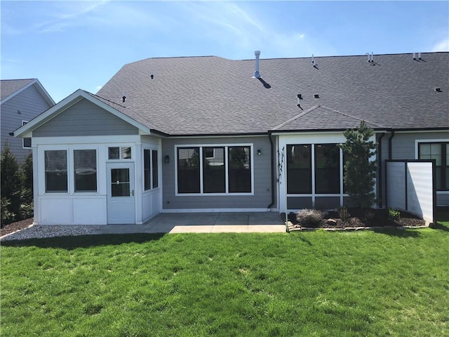 rear view of house featuring a lawn, roof with shingles, and a patio area