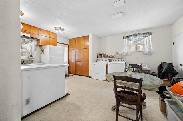 kitchen featuring a textured ceiling, white refrigerator, independent washer and dryer, and plenty of natural light