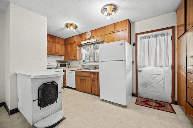 kitchen featuring sink, white appliances, and a textured ceiling