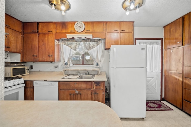 kitchen with a textured ceiling, sink, and white appliances