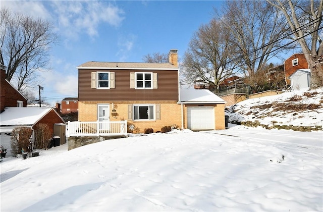 snow covered house featuring a garage