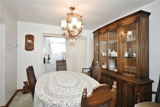 dining space with light carpet and a chandelier