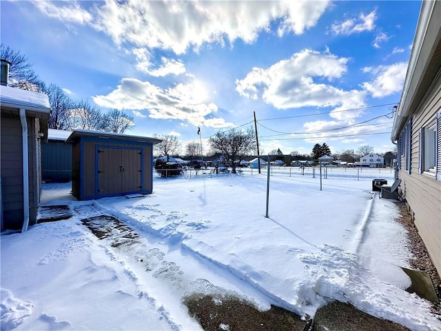 snowy yard featuring a storage shed