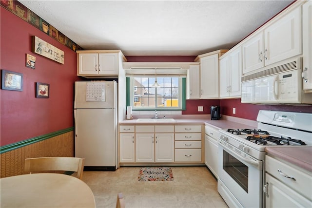 kitchen featuring white cabinets, sink, and white appliances