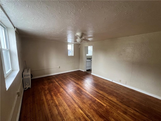 spare room featuring ceiling fan, dark hardwood / wood-style flooring, radiator heating unit, and a textured ceiling