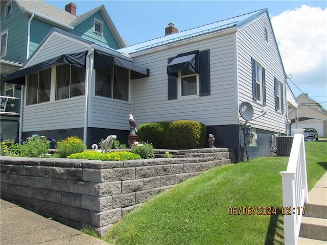 view of side of home featuring a lawn and central AC