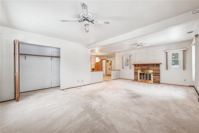 unfurnished living room featuring ceiling fan, light carpet, and a stone fireplace