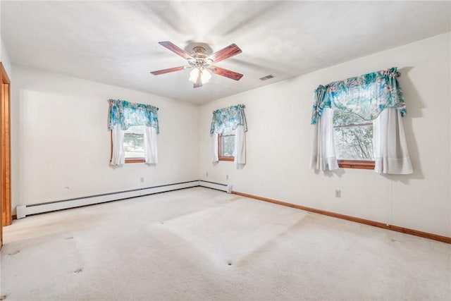 spare room featuring a baseboard heating unit, ceiling fan, a wealth of natural light, and light colored carpet