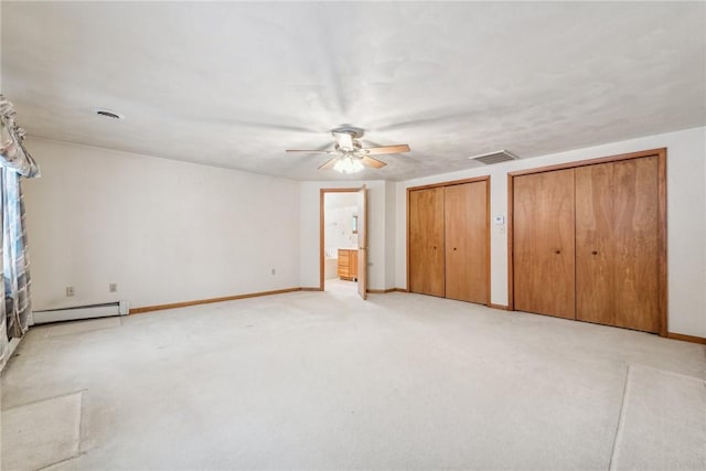 unfurnished bedroom with baseboard heating, two closets, connected bathroom, ceiling fan, and light colored carpet