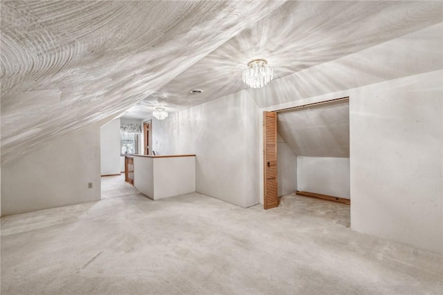 additional living space with light colored carpet, lofted ceiling, and an inviting chandelier