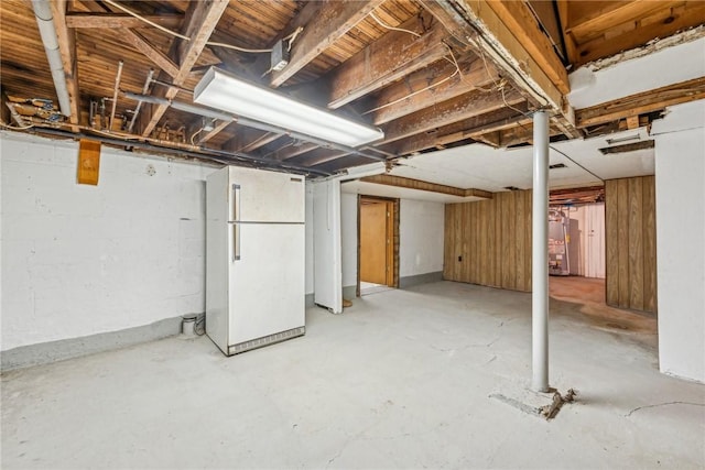 basement featuring water heater and white fridge