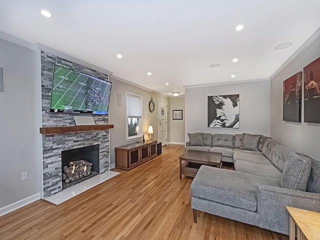 living room featuring a stone fireplace, ornamental molding, and hardwood / wood-style floors