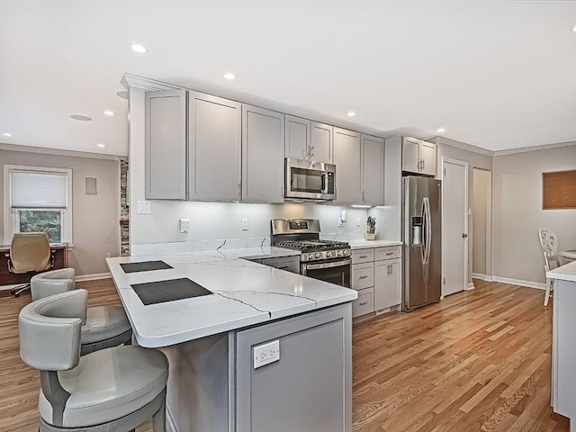 kitchen featuring kitchen peninsula, light wood-type flooring, light stone countertops, appliances with stainless steel finishes, and gray cabinetry