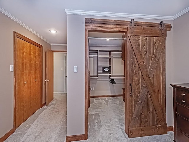 corridor with ornamental molding, light carpet, and a barn door