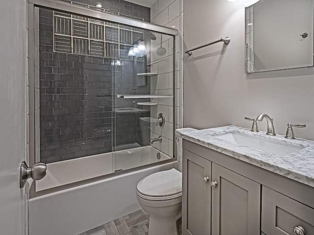 full bathroom featuring toilet, combined bath / shower with glass door, and vanity