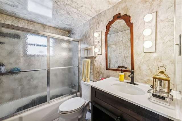 full bathroom featuring bath / shower combo with glass door, toilet, and vanity