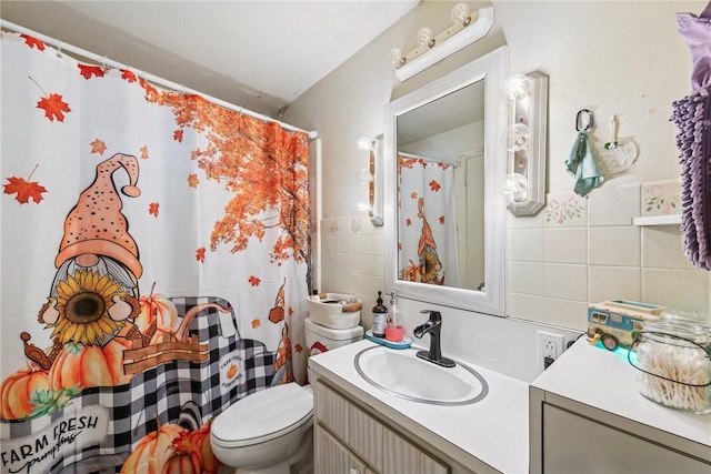 bathroom with toilet, vanity, and tile walls