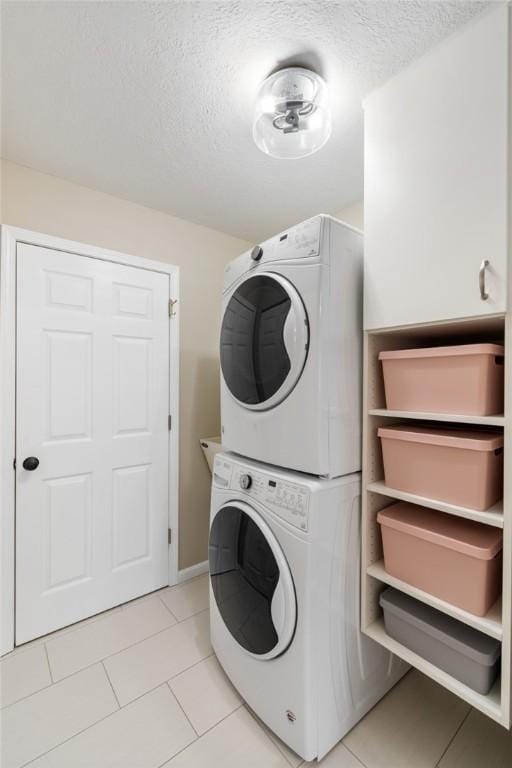 laundry room featuring light tile patterned floors, stacked washer and clothes dryer, and a textured ceiling