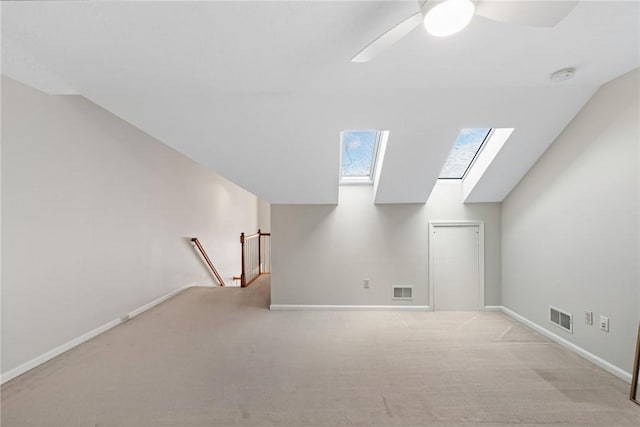 additional living space featuring ceiling fan, vaulted ceiling with skylight, and light carpet