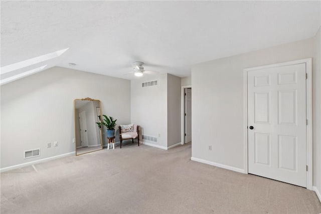 additional living space featuring light carpet, ceiling fan, and lofted ceiling with skylight