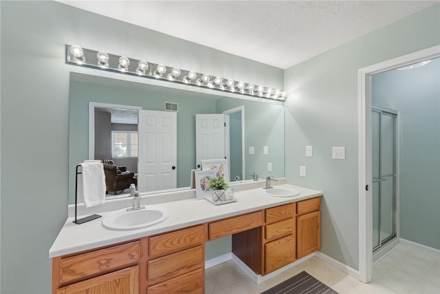 bathroom featuring a shower with shower door, vanity, and a textured ceiling