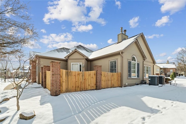 snow covered house featuring central AC unit