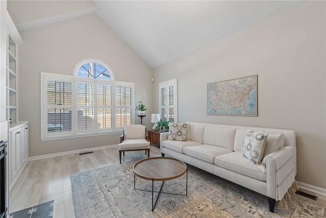 living room featuring light hardwood / wood-style floors, high vaulted ceiling, and a premium fireplace