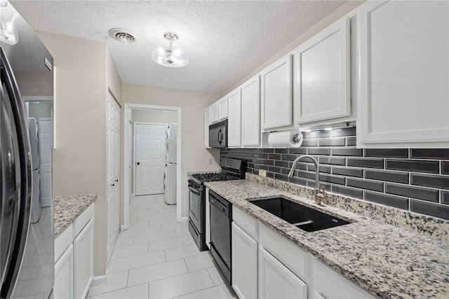 kitchen with light stone countertops, a textured ceiling, white cabinets, black appliances, and sink