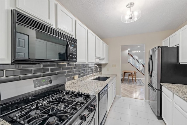 kitchen with white cabinetry, decorative backsplash, light stone countertops, black appliances, and sink